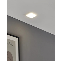 Plafonieră LED pătrată modernă cu design plat, aprinsă și montată pe tavan lângă un tablou înrămat.