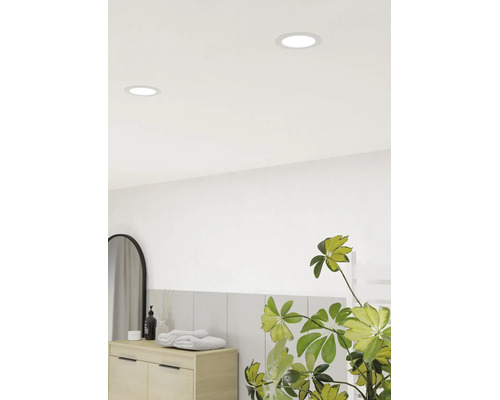 Baie luminoasă cu spoturi LED rotunde încastrate în tavan, un dulap din lemn, prosoape, o oglindă arcuită și o plantă de apartament.
