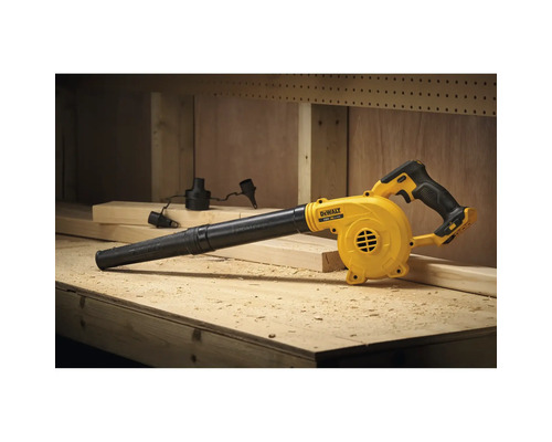 Suflantă cu acumulator DeWalt pe un banc de lucru din lemn într-un atelier cu așchii de lemn și diferite duze.