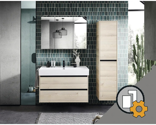 Set mobilier baie modern aspect lemn deschis cu mască chiuvetă, lavoar alb, dulap oglindă și dulap înalt pe fundal de faianță verde.