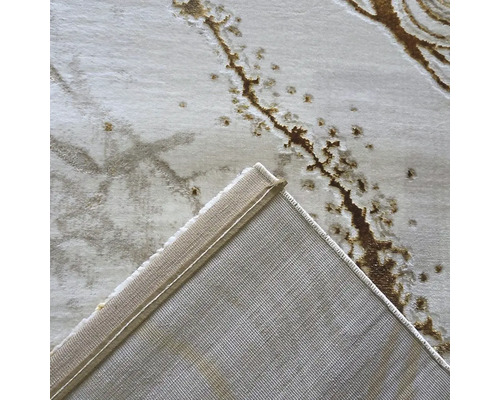 Vedere detaliată a unui covor cu model abstract și un colț îndoit care arată spatele textil țesut.
