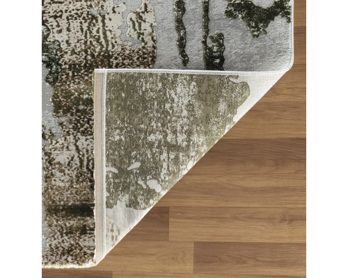 Covor modern cu fir scurt, cu model abstract pe podea de lemn, colț pliat cu spatele vizibil.