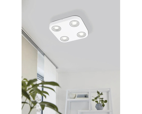 Plafonieră LED modernă pătrată cu patru surse de lumină rotunde într-o cameră luminoasă cu raft și plante de apartament.