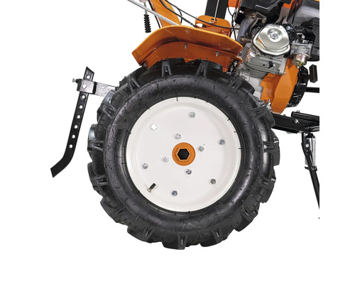 Vedere de aproape a unei roți de motocultor cu profil adânc și jantă albă, inclusiv părți ale motorului și carcasei portocalii.