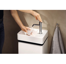 O persoană umple un pahar cu apă de la o baterie cromată de pe un lavoar mic de culoare albă, prevăzut cu un dulap de mascare asortat.