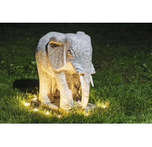 Statuie de grădină elefant din piatră cu iluminare pe un gazon noaptea.