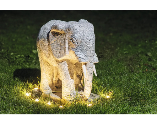 Statuie de grădină elefant din piatră cu iluminare pe un gazon noaptea.