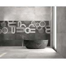 Baie modernă cu plăci de faianță de dimensiuni mari, plăci decorative cu modele geometrice, cadă de sine stătătoare și baterie de pardoseală.