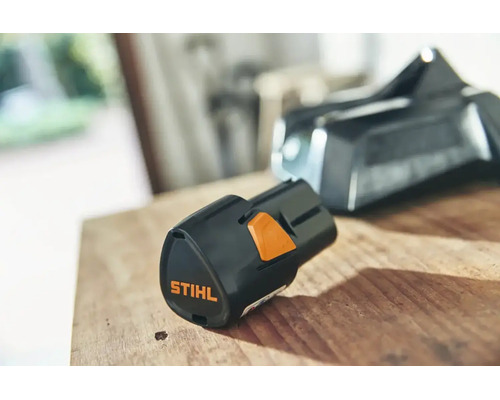 Acumulator litiu-ion Stihl AS 2 pentru sistemul AS pe o suprafață de lemn.
