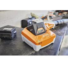 Încărcător rapid STIHL AL 301 cu acumulator AK 30 introdus pe un banc de lucru într-un atelier.