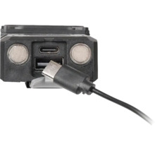 Vedere de aproape a unui dispozitiv negru cu port de încărcare USB-C și USB-A și două contacte metalice rotunde cu un cablu USB-C conectat.