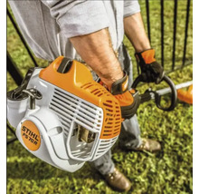 Persoană care utilizează o motocoasă pe benzină STIHL FS 70 R pentru îngrijirea gazonului într-o grădină luminoasă.