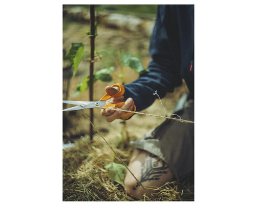 O persoană taie o sfoară cu o foarfecă universală în timp ce lucrează în grădină.