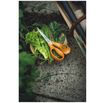 Foarfecă pentru ierburi Fiskars așezată pe ierburi și salată proaspăt recoltate într-un bol în grădină, pe o podea de piatră.