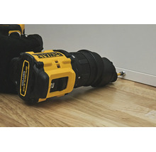 Mașină de găurit și înșurubat cu acumulator DeWalt cu atașament excentric înșurubează un șurub într-un panou alb pe o suprafață de lemn.