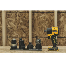 Mașină de găurit și înșurubat DeWalt 18 Volți XR fără perii cu patru accesorii interschimbabile pe o suprafață de lemn în fața unui perete OSB.