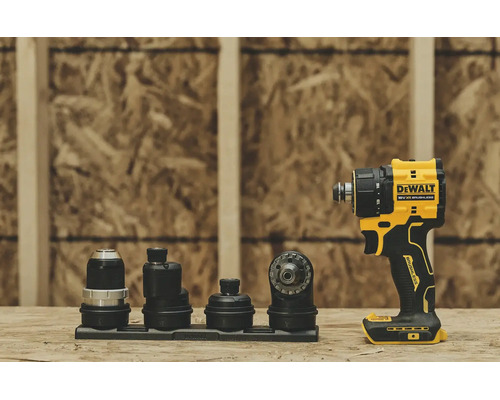 Mașină de găurit și înșurubat DeWalt 18 Volți XR fără perii cu patru accesorii interschimbabile pe o suprafață de lemn în fața unui perete OSB.