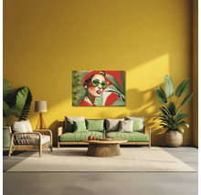 Sufragerie modernă cu perete galben, canapea verde, fotoliu din ratan și un tablou pop art cu o femeie cu ochelari de soare.