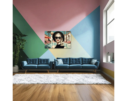 Sufragerie modernă luminoasă cu perete geometric colorat, două canapele din catifea albastră, covor alb pufos și tablou modern pe pânză.