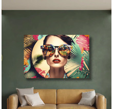 Tablou modern cu o femeie cu ochelari de soare și motive tropicale deasupra unei canapele pe un perete verde.