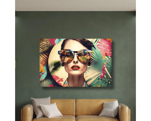 Tablou modern cu o femeie cu ochelari de soare și motive tropicale deasupra unei canapele pe un perete verde.