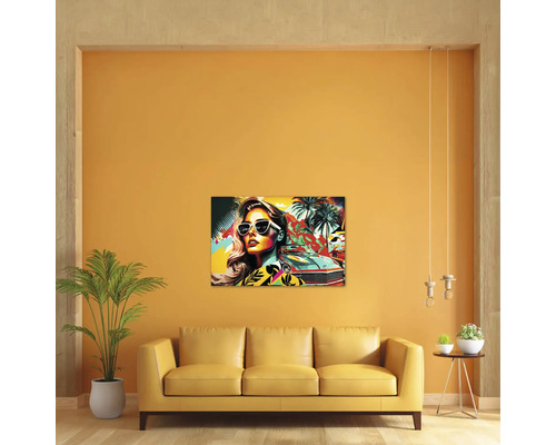 Living modern cu un tablou pe pânză pop art colorat cu o femeie, o mașină și palmieri deasupra unei canapele galbene.