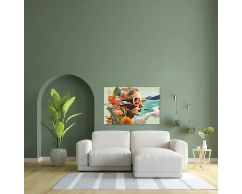 Living modern cu perete verde, canapea albă și un tablou cu un portret de tip colaj al unei femei deasupra canapelei.