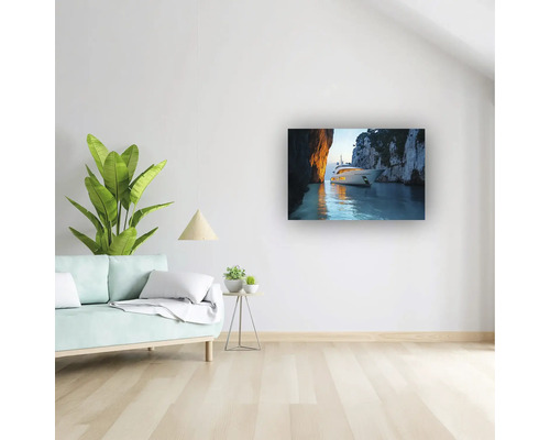 Cameră de zi modernă și luminoasă cu un tablou cu un iaht într-un golf, canapea, plantă de interior și pardoseală cu aspect de lemn.