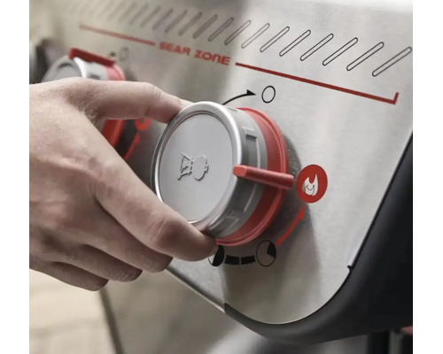 Mână care rotește butonul de control pentru Sear Zone la un grătar cu gaz Weber cu Weber Logo.