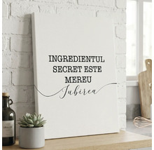 Tablou canvas cu textul Ingredientul secret este mereu iubirea așezat într-un decor de bucătărie lângă o plantă și o sticlă de ulei de măsline.