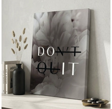 Tablou pe panza cu motiv floral si textul DO IT creat din DONT QUIT pe un raft langa vaza neagra si carti intr-un mediu luminos.