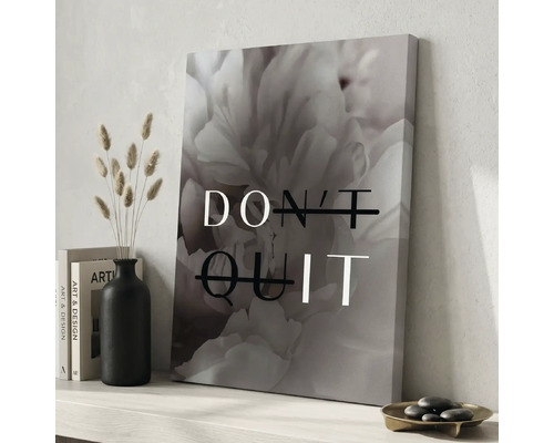 Tablou pe panza cu motiv floral si textul DO IT creat din DONT QUIT pe un raft langa vaza neagra si carti intr-un mediu luminos.