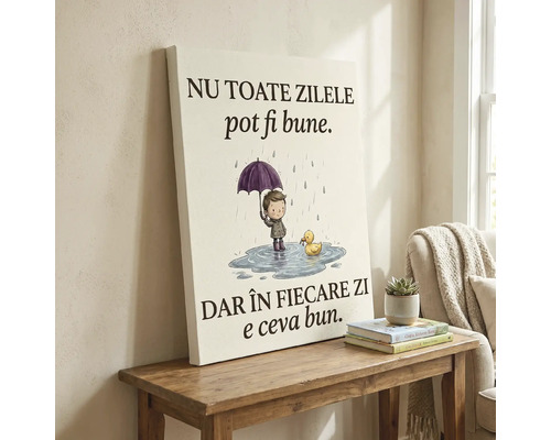 Tablou pe pânză cu ilustrație cu un băiețel în ploaie și mesaj în limba română, așezat pe o masă din lemn lângă o plantă.