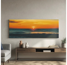 Tablou canvas panoramic cu apus de soare peste mare, deasupra unei comode din lemn într-un living mobilat modern.