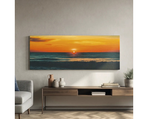 Tablou canvas panoramic cu apus de soare peste mare, deasupra unei comode din lemn într-un living mobilat modern.
