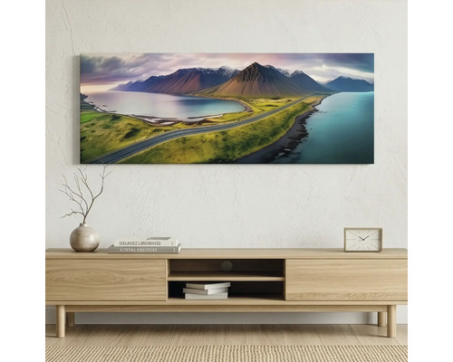 Tablou pe pânză panoramic cu peisaj de munte și apă deasupra unei comode din lemn într-o cameră luminoasă, mobilată modern.