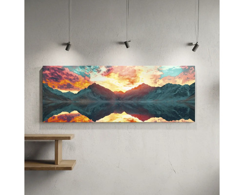 Tablou panoramic pe pânză cu peisaj montan la apus și reflexie în apă, iluminat de spoturi pe un perete deasupra unui raft.