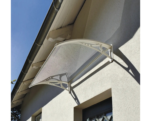 Copertină curbată pentru ușă cu înveliș transparent și suporturi ornamentate pe un perete exterior.