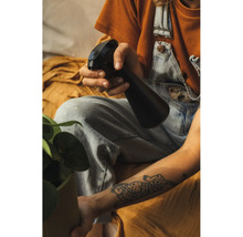 O persoană stropește o plantă de interior cu un pulverizator din plastic.