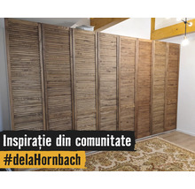 Dulap mare cu uși lamelare din lemn într-o cameră luminoasă, cu un covor cu model și grinzi de lemn pe tavan. Hornbach Logo.