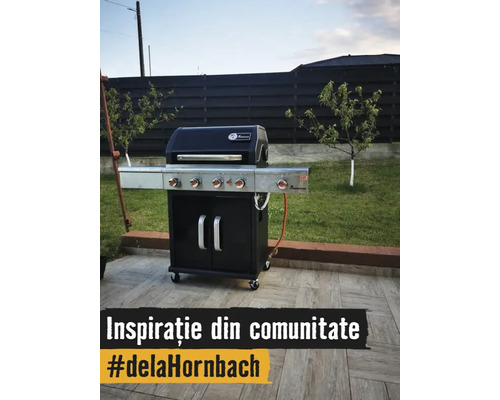 Grătar pe gaz Landmann pe o terasă pavată, cu grădina în fundal.