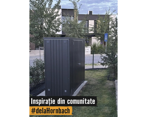 Căsuță de grădină modernă din metal gri închis amplasată pe gazon în curtea unei case.