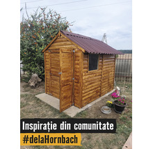 Căsuță de grădină din lemn cu acoperiș în două ape și ușă deschisă pe o fundație de beton în grădină.