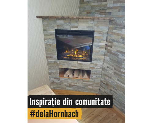 Șemineu electric încorporat într-un perete cu placaj de piatră, cu poliță de lemn și spațiu pentru depozitarea lemnelor.