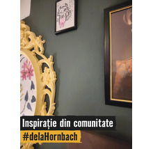 Decor de perete cu diverse rame foto pe un perete verde închis, inclusiv o ramă ovală galbenă, decorată, cu motiv floral.