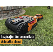 Robot de tuns gazonul cu roți pentru teren accidentat pe o peluză lângă o mașină de jucărie.