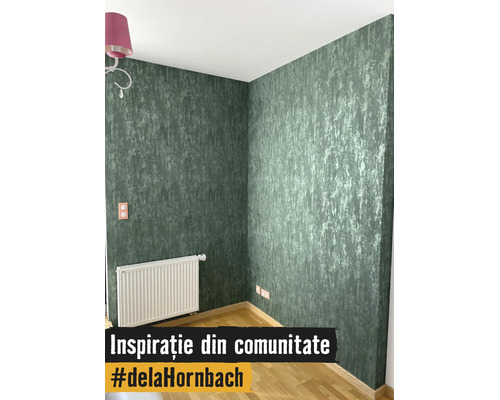 Scenă de interior cu tapet verde texturat, un radiator alb și pardoseală din lemn de culoare deschisă într-un colț de cameră luminos.