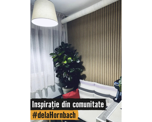 Living modern cu panou de perete din lamele verticale de lemn, plantă de apartament, perdele albe și canapea cu perne în dungi.