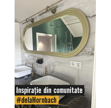 Baie modernă cu două lavoare albe, baterii aurii și o oglindă ovală mare cu ramă aurie pe un perete cu aspect de marmură.