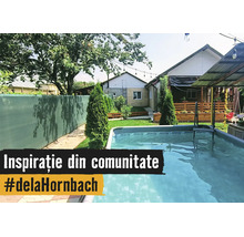 O grădină luminoasă cu o piscină supraterană dreptunghiulară, paravan verde, gazon cu tuia și o terasă din lemn în fața casei.
